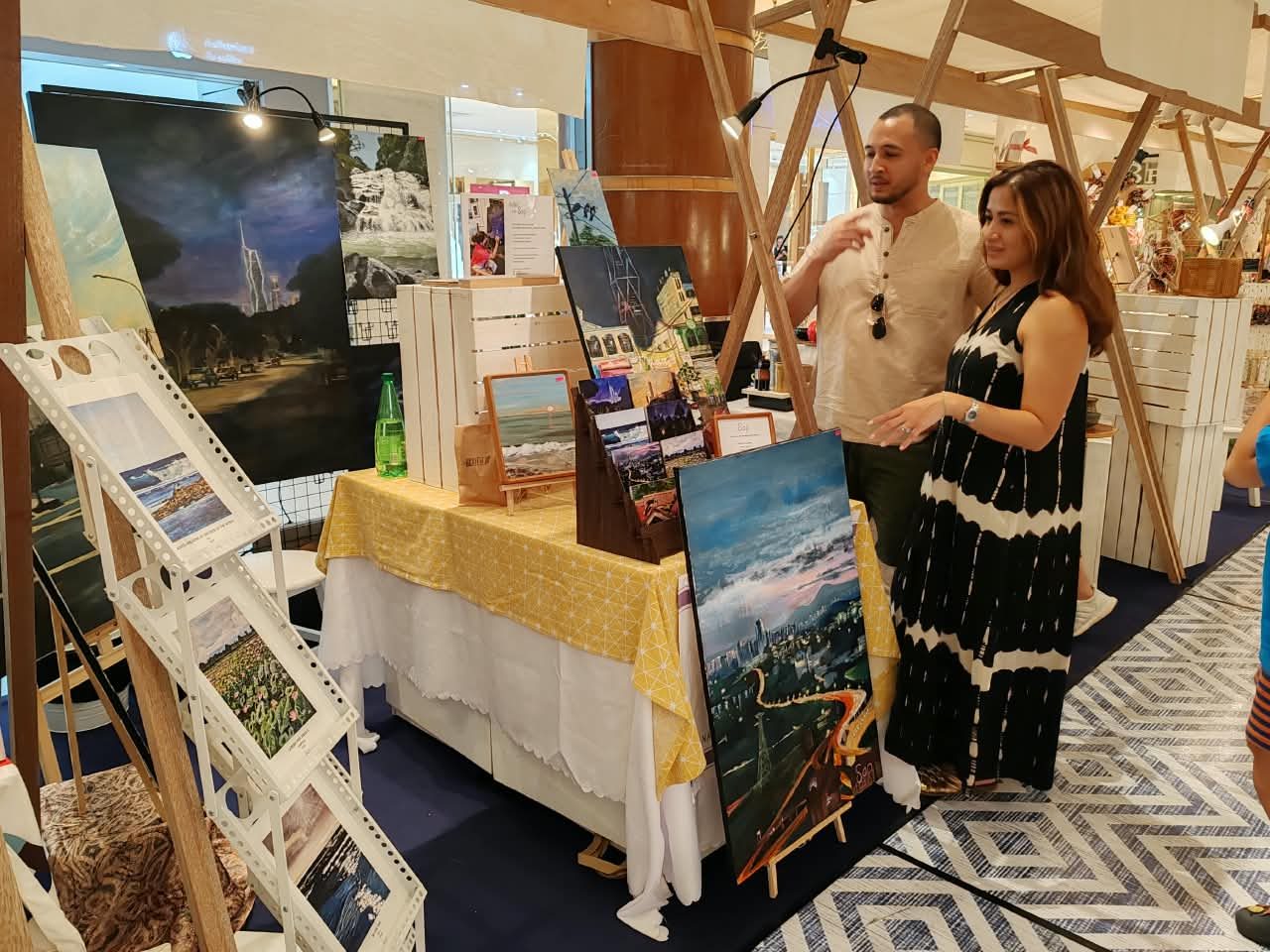 Visitors looking at Sap's paintings at her market booth